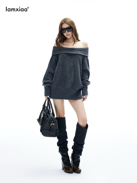 Model wearing a dark off-shoulder knit sweater dress with tall boots and a handbag