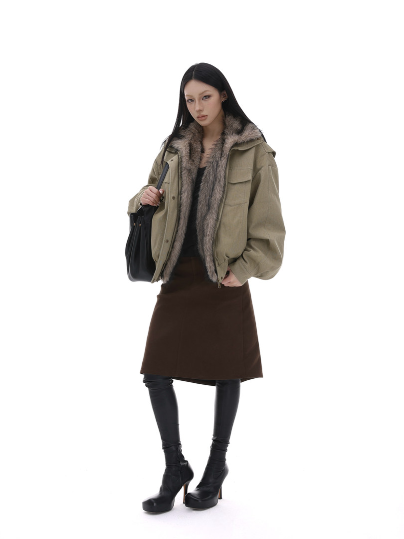 Model wearing an olive fur-lined jacket with skirt and boots on a white background