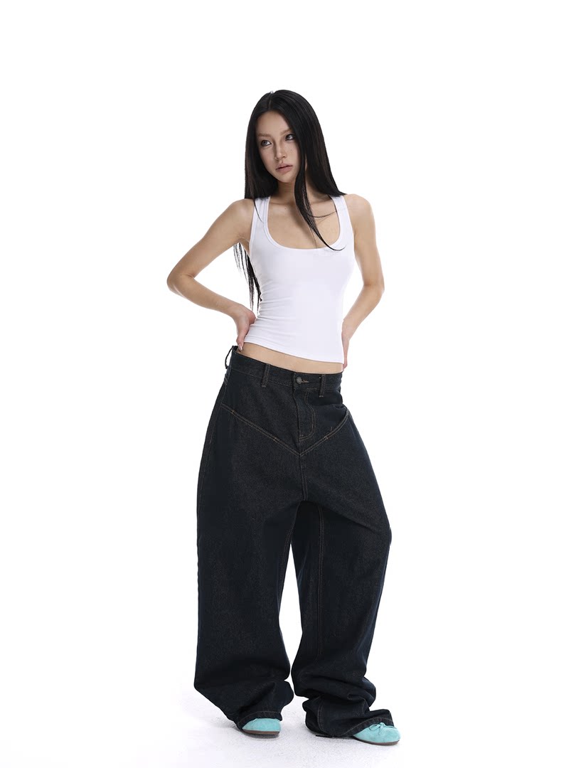 Model wearing a white tank top with oversized black jeans