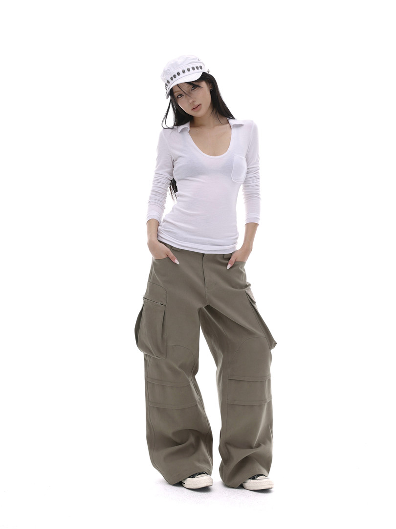 Female model wearing white fitted top, olive cargo pants, and a white cap on a white background