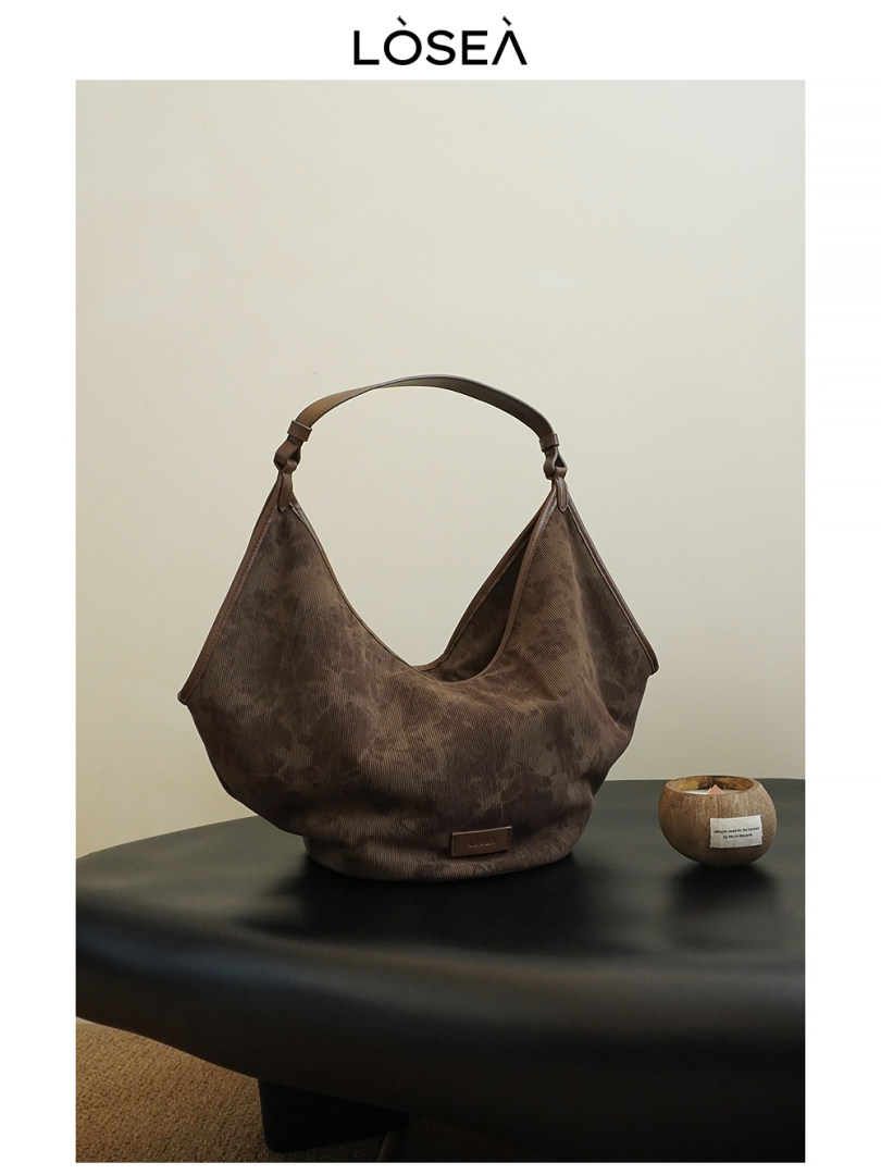 Brown slouchy shoulder handbag displayed on a table