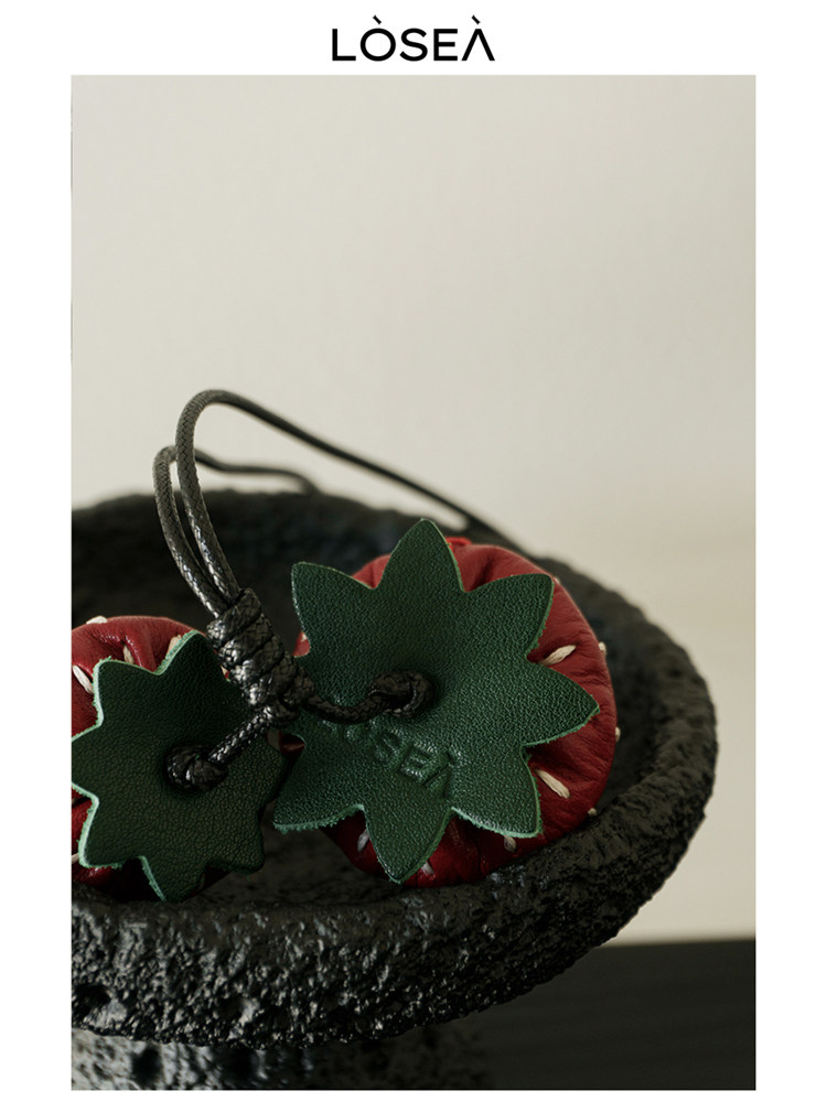 Black textured handbag with strawberry charm detail
