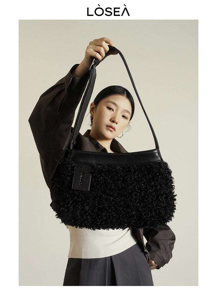 Black fuzzy shoulder handbag worn by a model