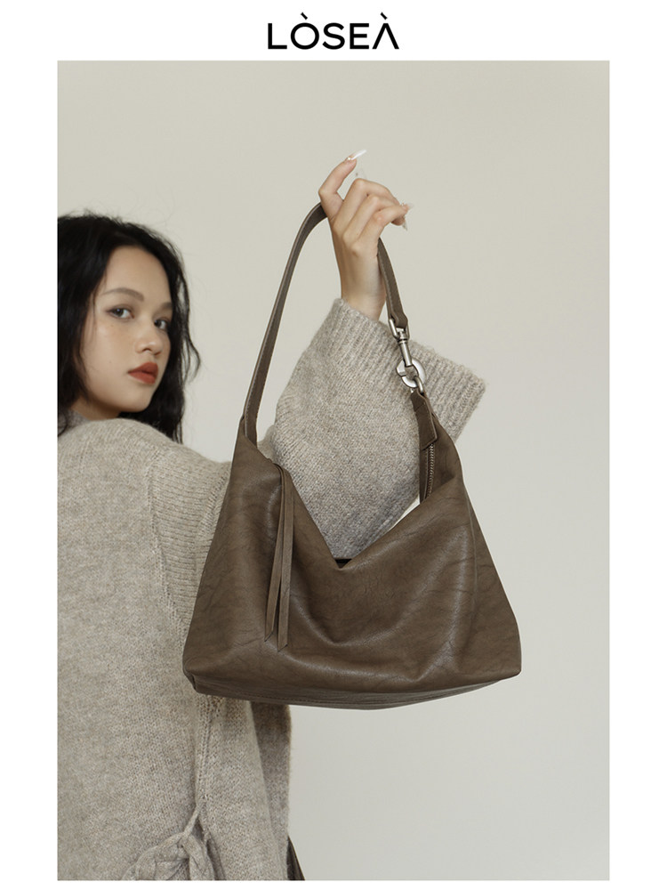 Brown leather shoulder handbag held by a model