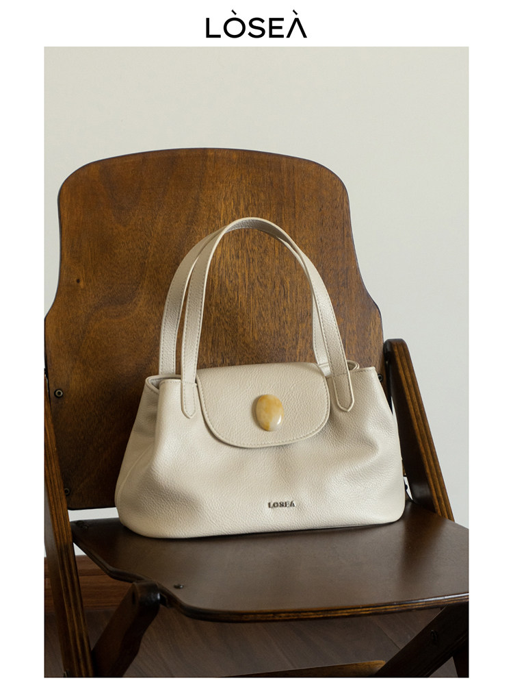 Cream leather handbag on a wooden chair