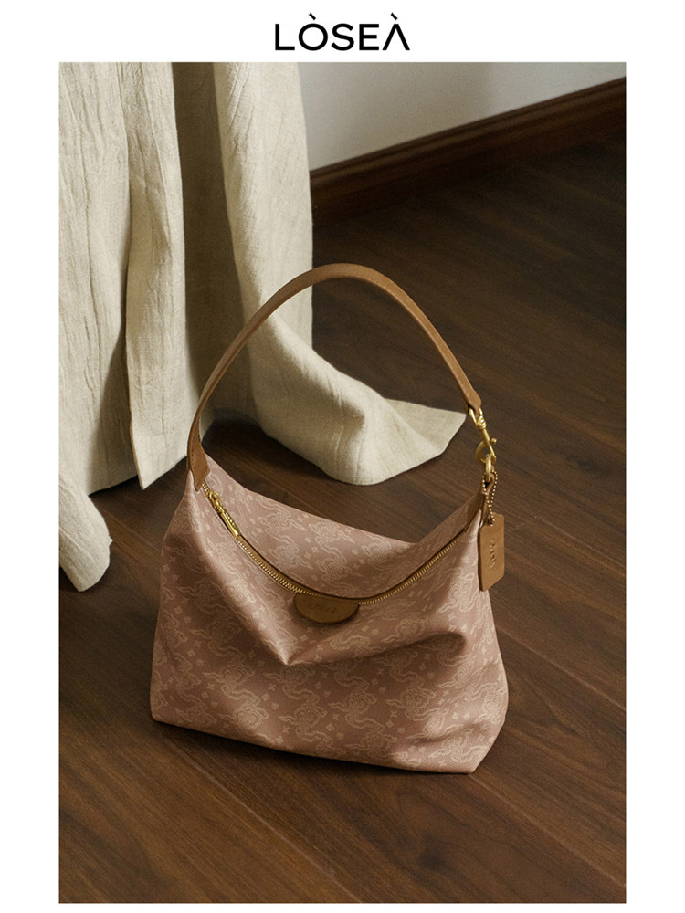 Pink monogram shoulder handbag with gold hardware on a wooden floor