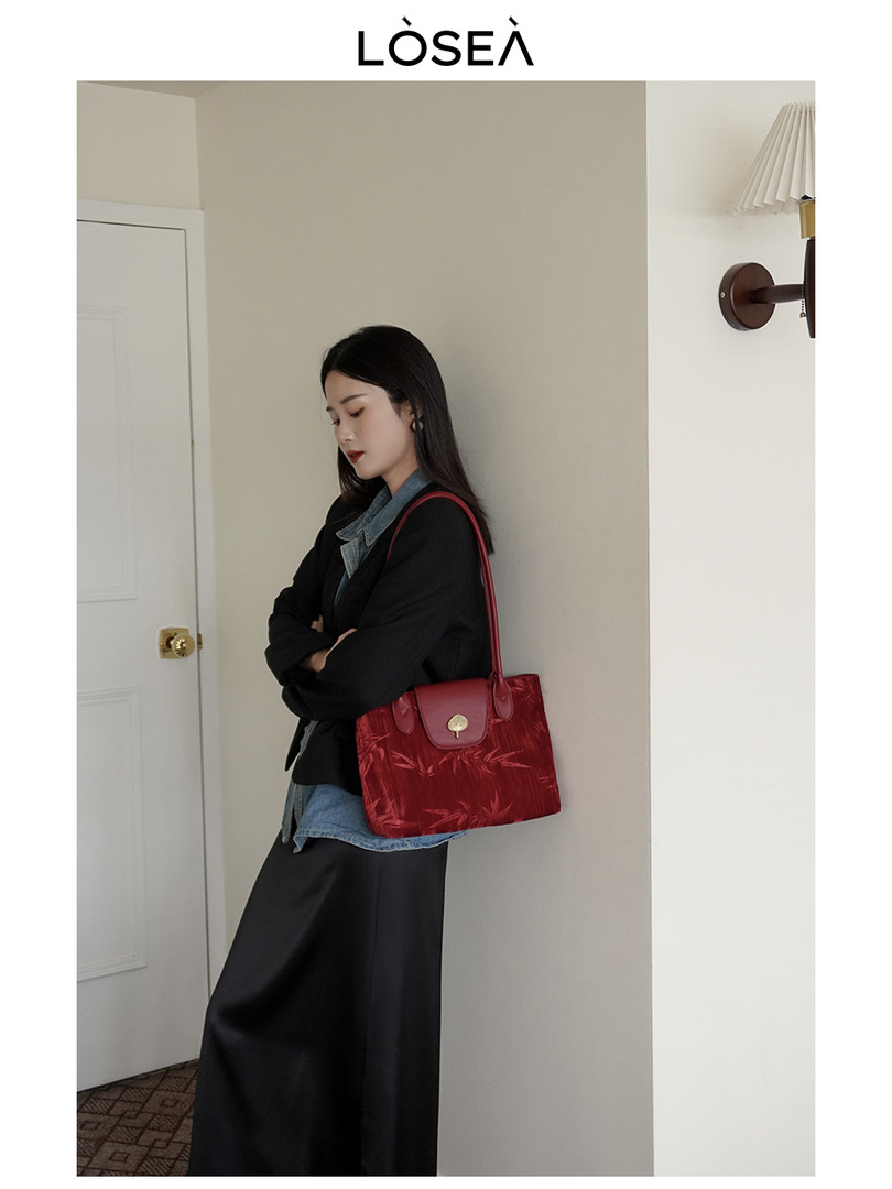 Woman wearing a red leather handbag with a black-and-denim outfit