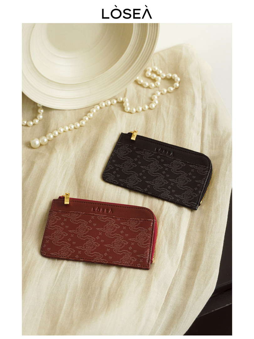 Two patterned zip card wallets laid flat on a light fabric surface