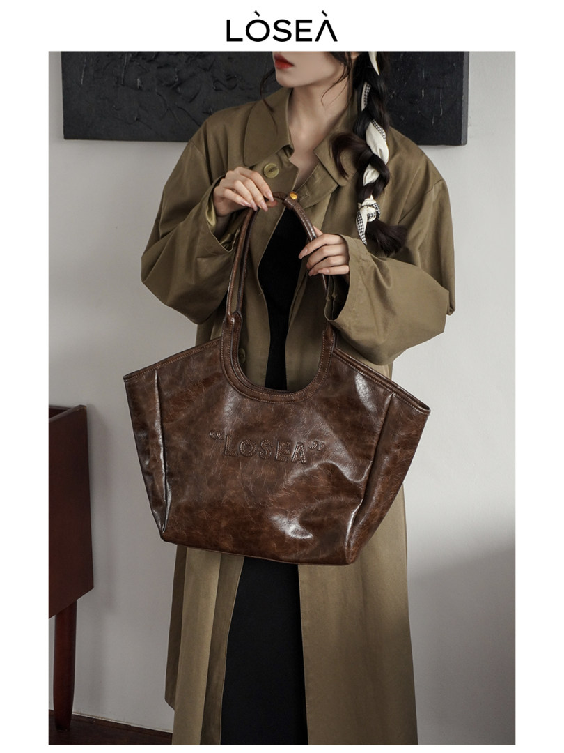 Brown leather tote bag held by a model