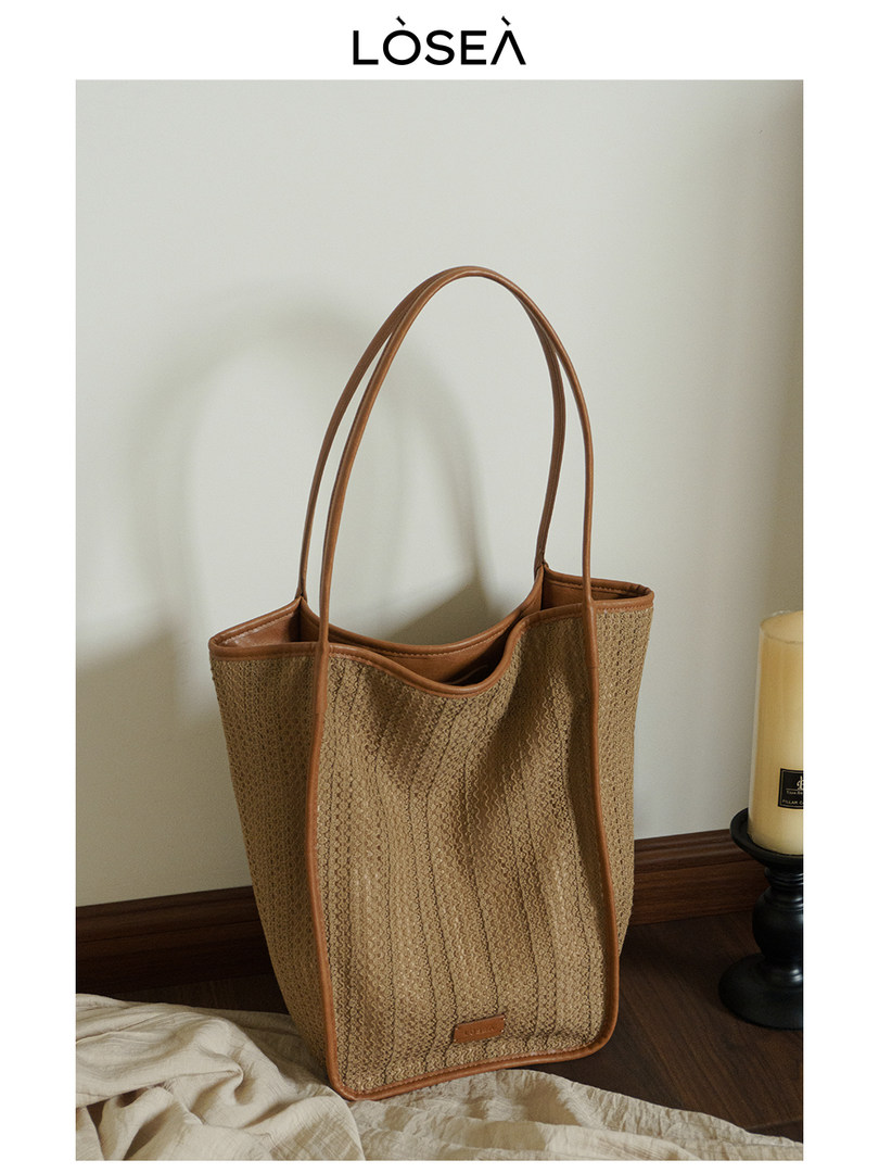 Brown woven tote bag with long handles on a neutral background