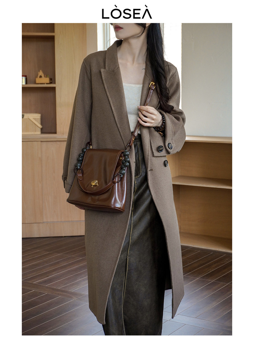 Woman wearing a brown long coat with a leather shoulder bag