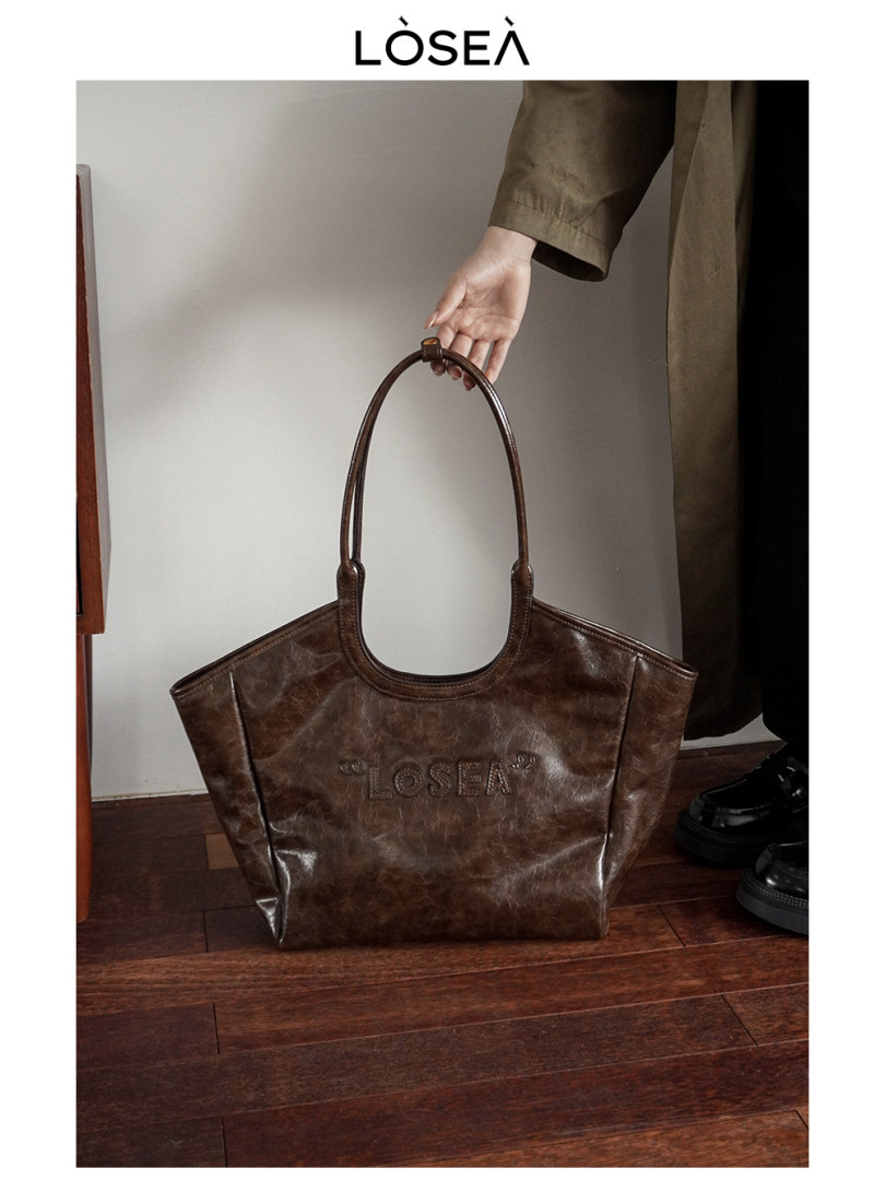 Brown leather tote handbag being held indoors