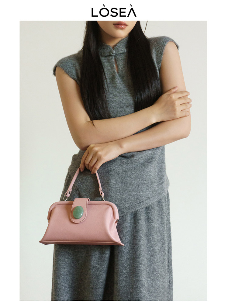 Model wearing a gray sleeveless knit outfit and holding a pink handbag