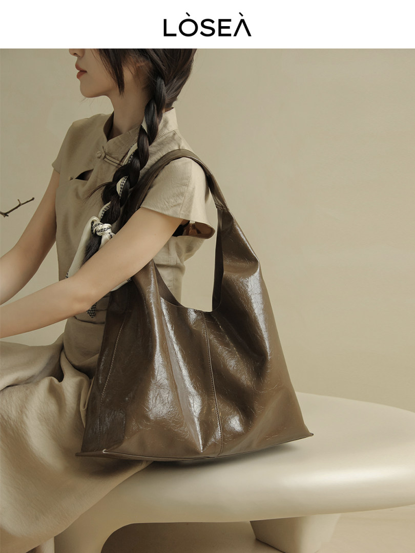 Brown oversized leather tote bag worn by a model
