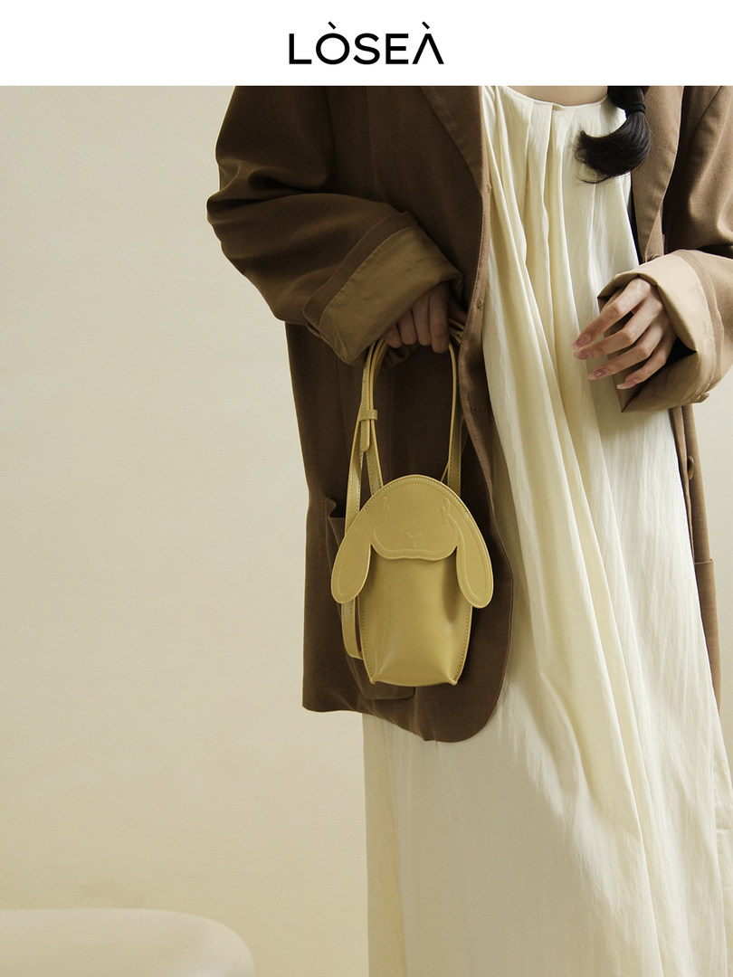 Yellow dog-shaped mini handbag held by a model