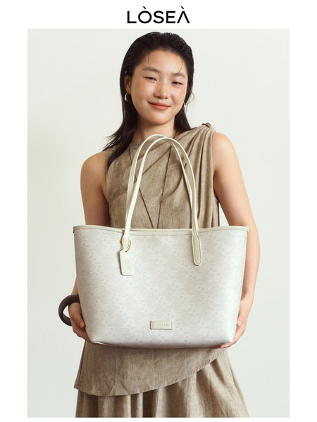 Model holding a light-colored structured tote bag