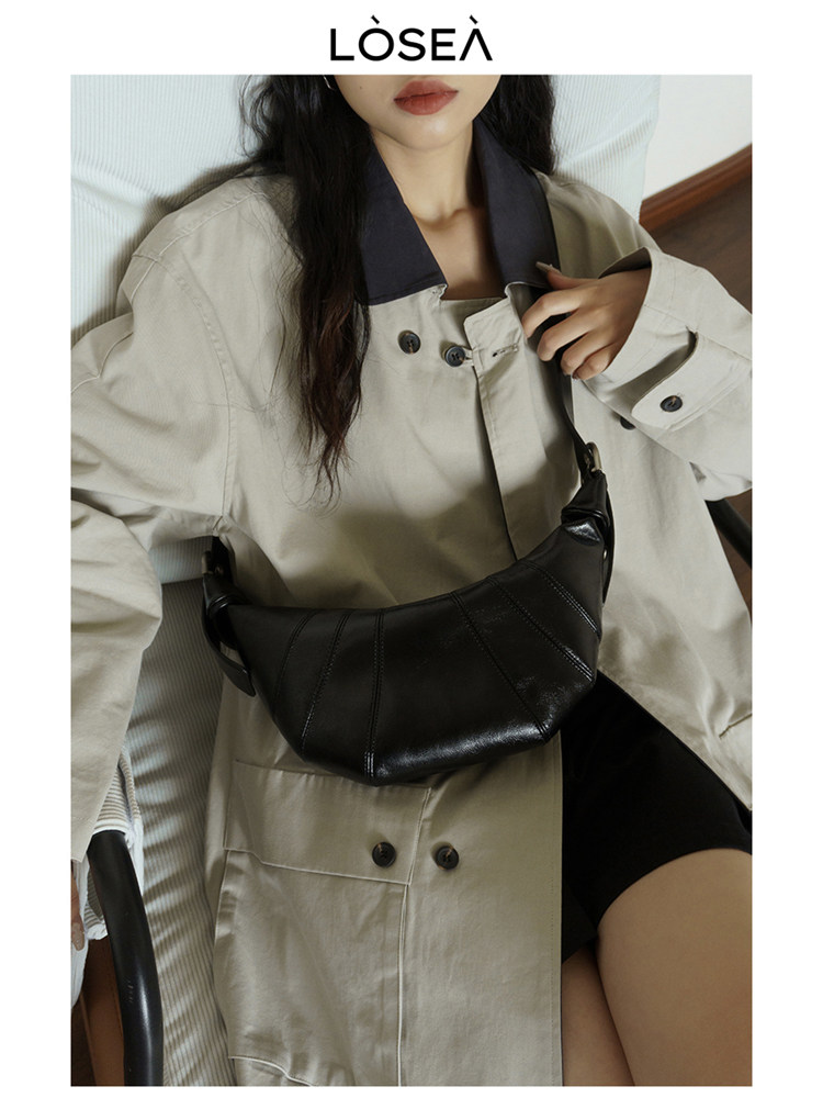 Model wearing a beige trench coat with a black crossbody bag