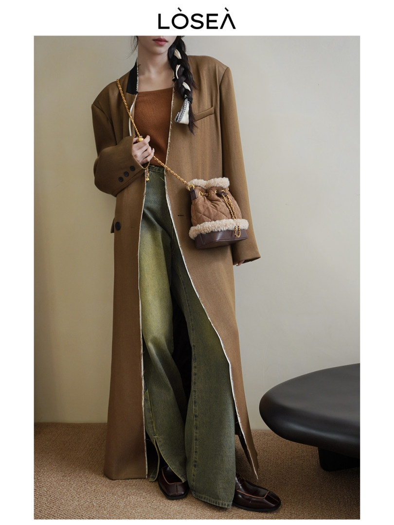 Woman wearing a long brown coat with layered outfit and a small shoulder bag