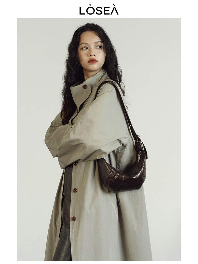 Model wearing a beige oversized coat with a dark brown shoulder bag