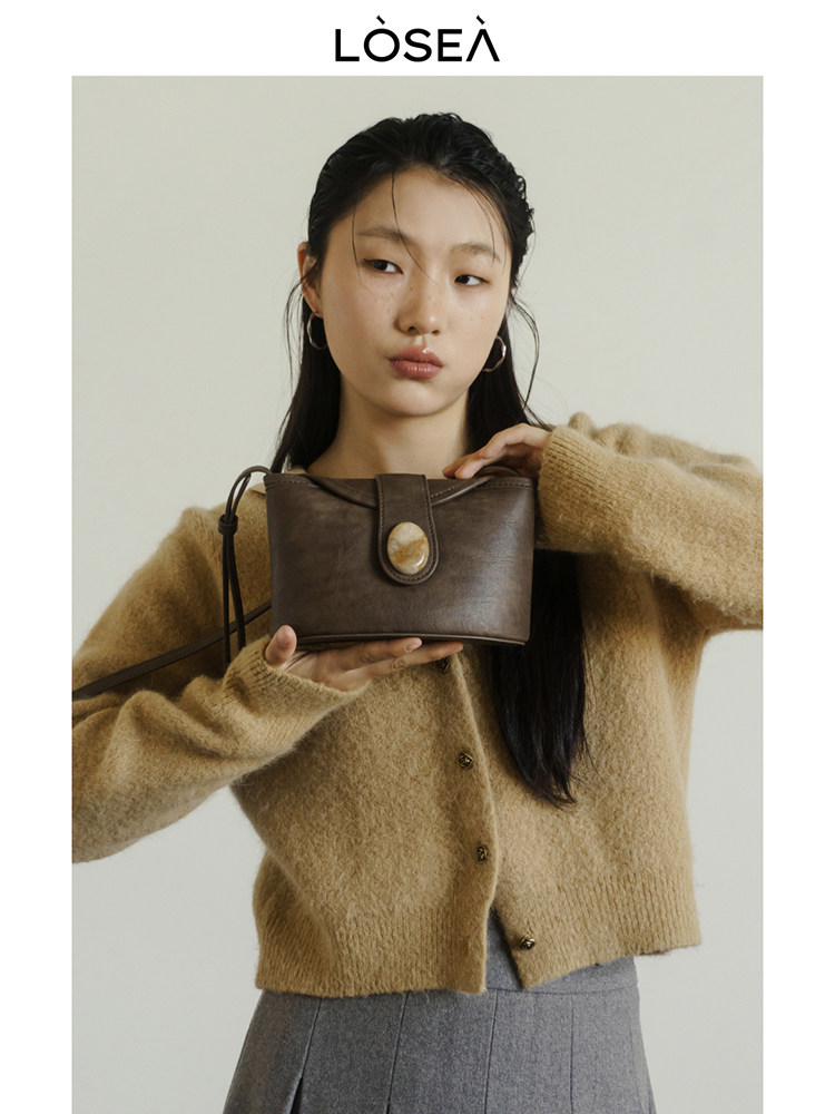 Model holding a small brown leather handbag