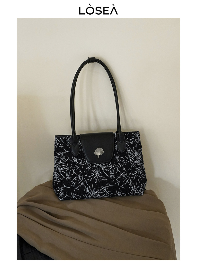 Black patterned tote handbag with long handles and flap closure