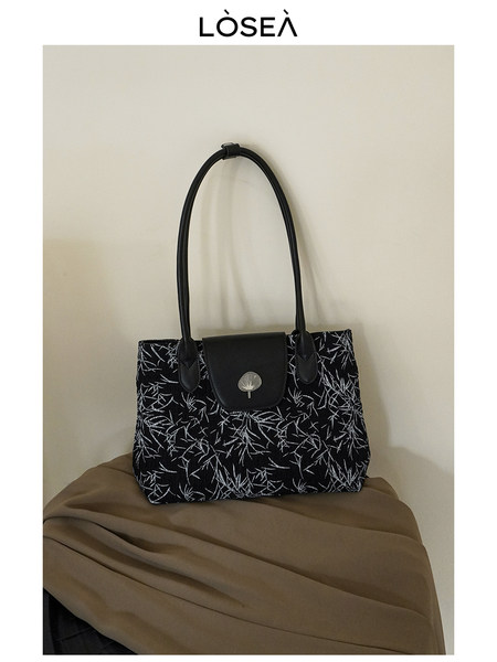 Black patterned tote handbag with long handles and flap closure