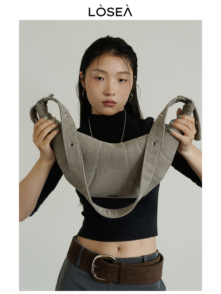 Model holding a gray shoulder handbag