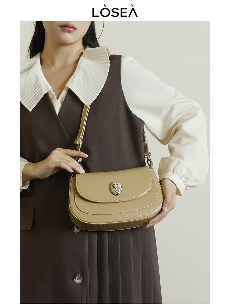 Beige shoulder handbag worn by a model with a dark dress and white blouse