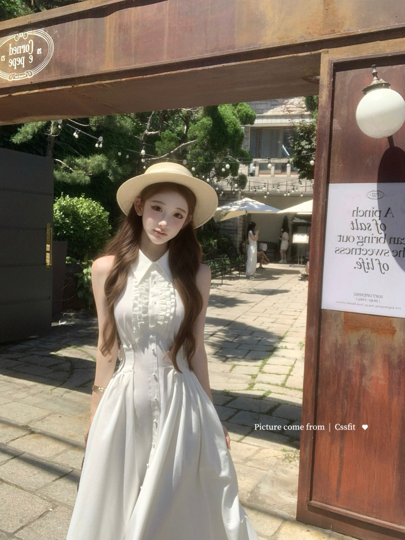 Woman wearing a white sleeveless maxi dress and straw hat outdoors