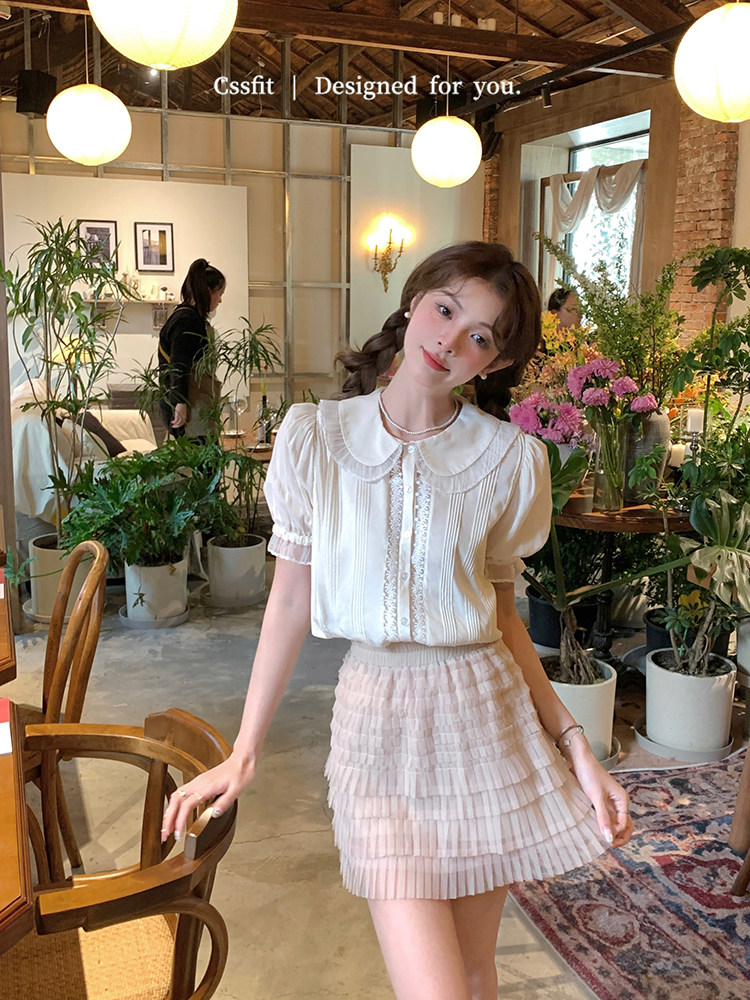 Woman wearing a white puff-sleeve blouse with a pleated mini skirt