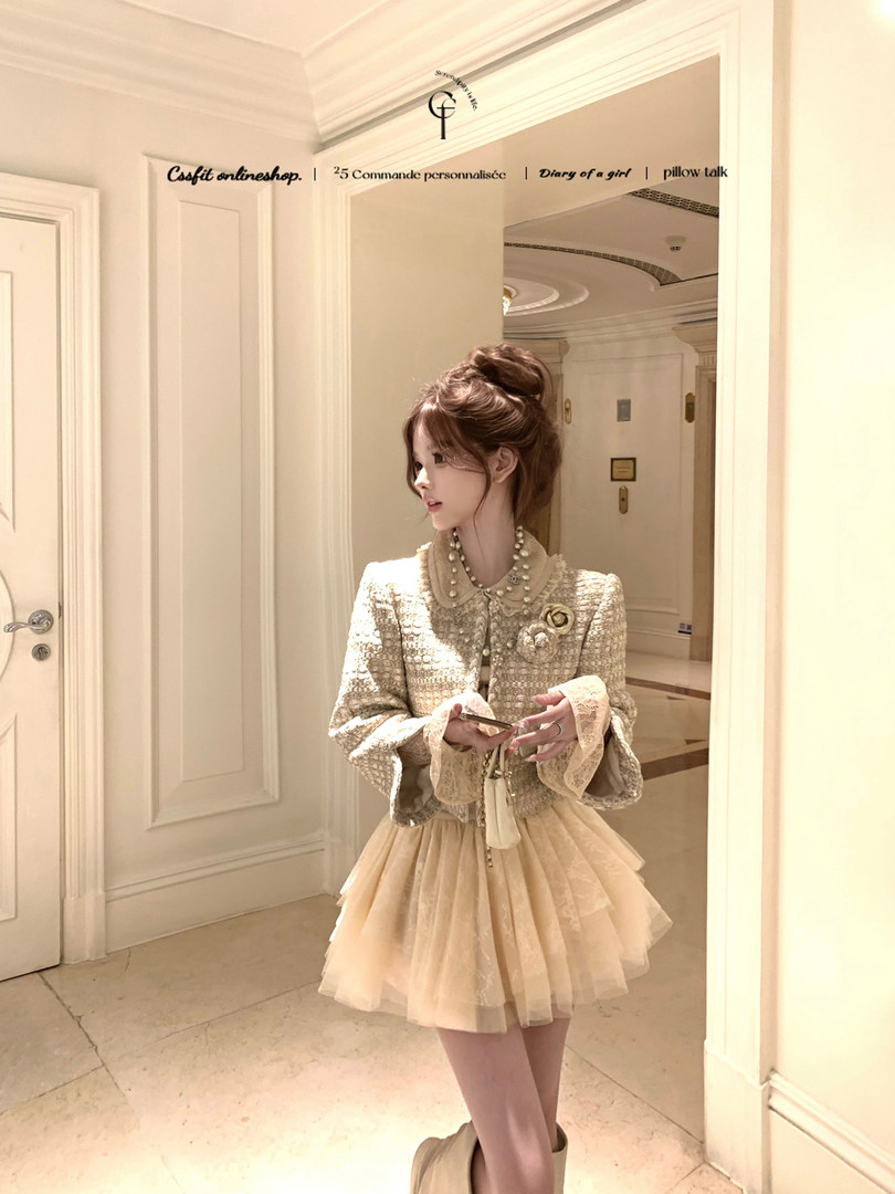 Model wearing a cream textured blouse and layered tulle skirt in an elegant indoor setting