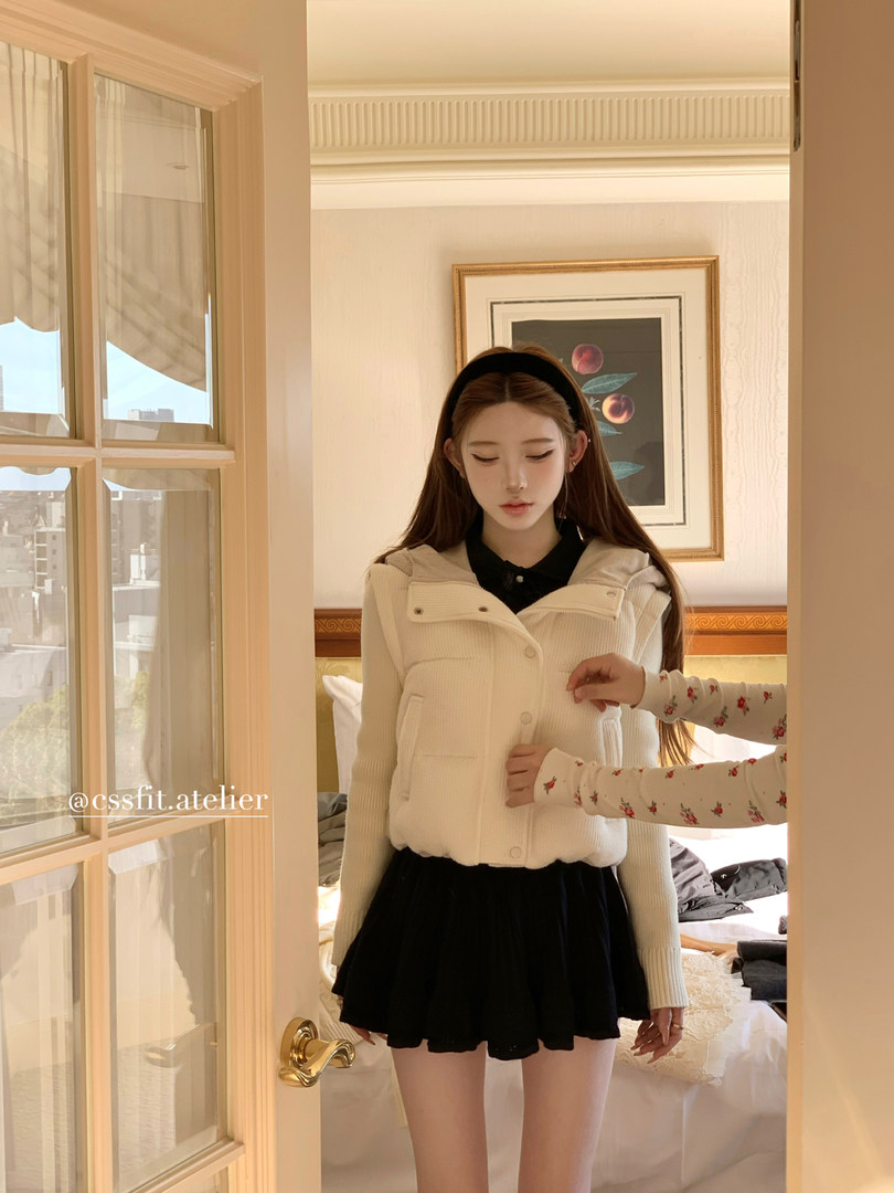 Model wearing a cream hooded puffer vest over a black outfit