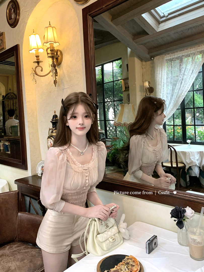 Woman wearing a light pink feminine two-piece outfit in a café setting