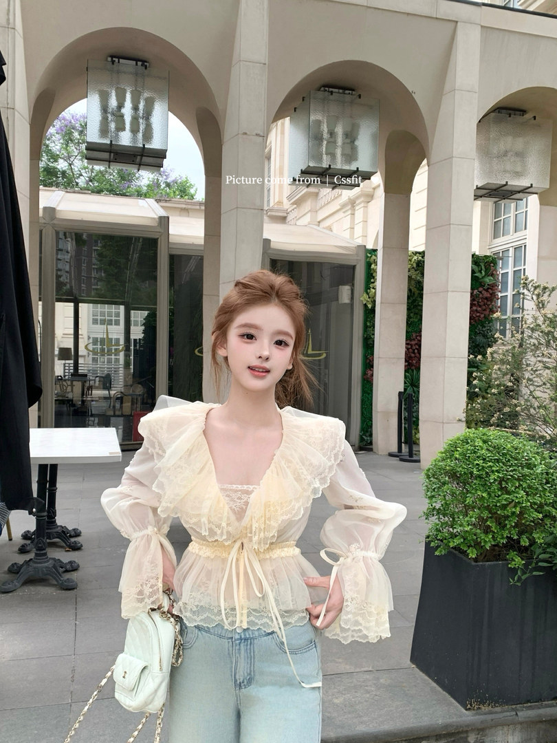 Cream sheer ruffled long-sleeve blouse worn with light blue jeans and a small white handbag