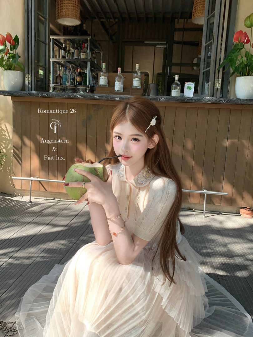 Model wearing a cream tulle dress while sitting outdoors with a coconut drink