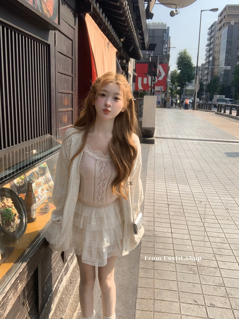 Woman wearing a cream lace dress with a matching cardigan outdoors
