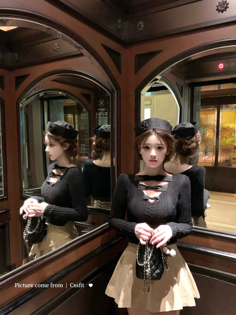 Model wearing a black long-sleeve top with bow details and a beige skirt