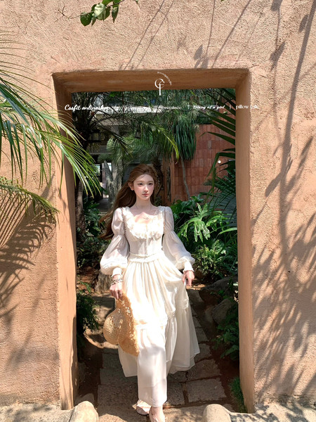 Woman wearing a white long-sleeve dress in a tropical garden