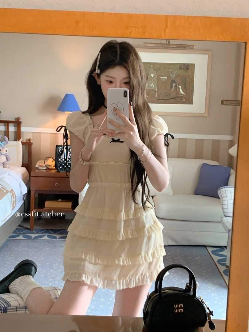 Woman wearing a cream ruffled short dress in a mirror selfie