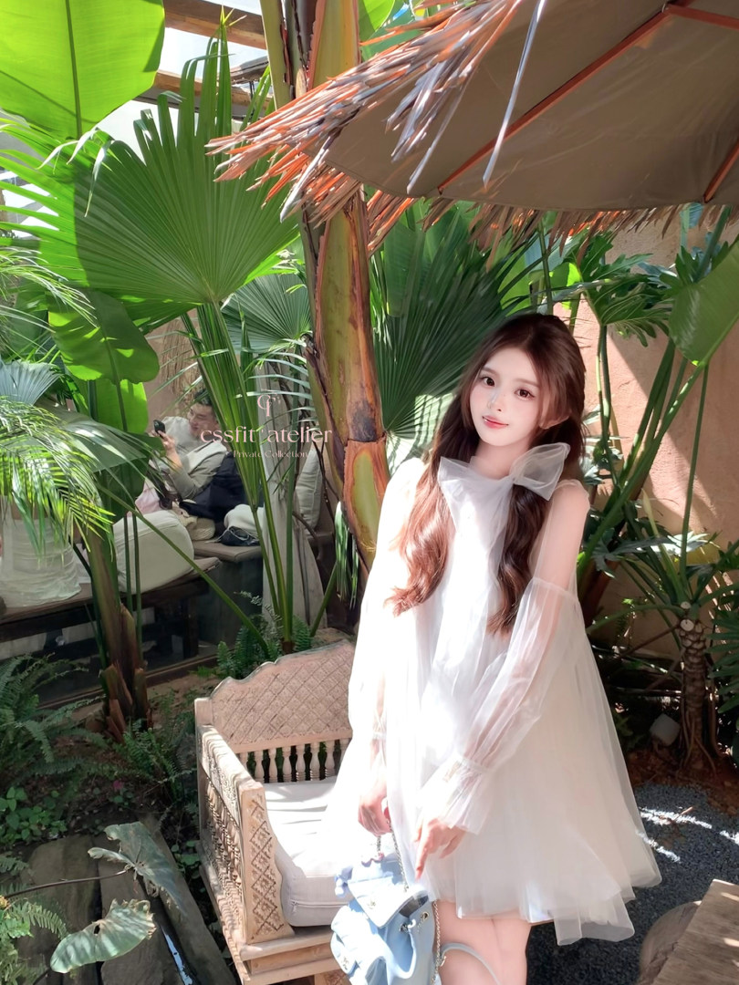 Woman wearing a white sheer tulle dress outdoors in a tropical setting
