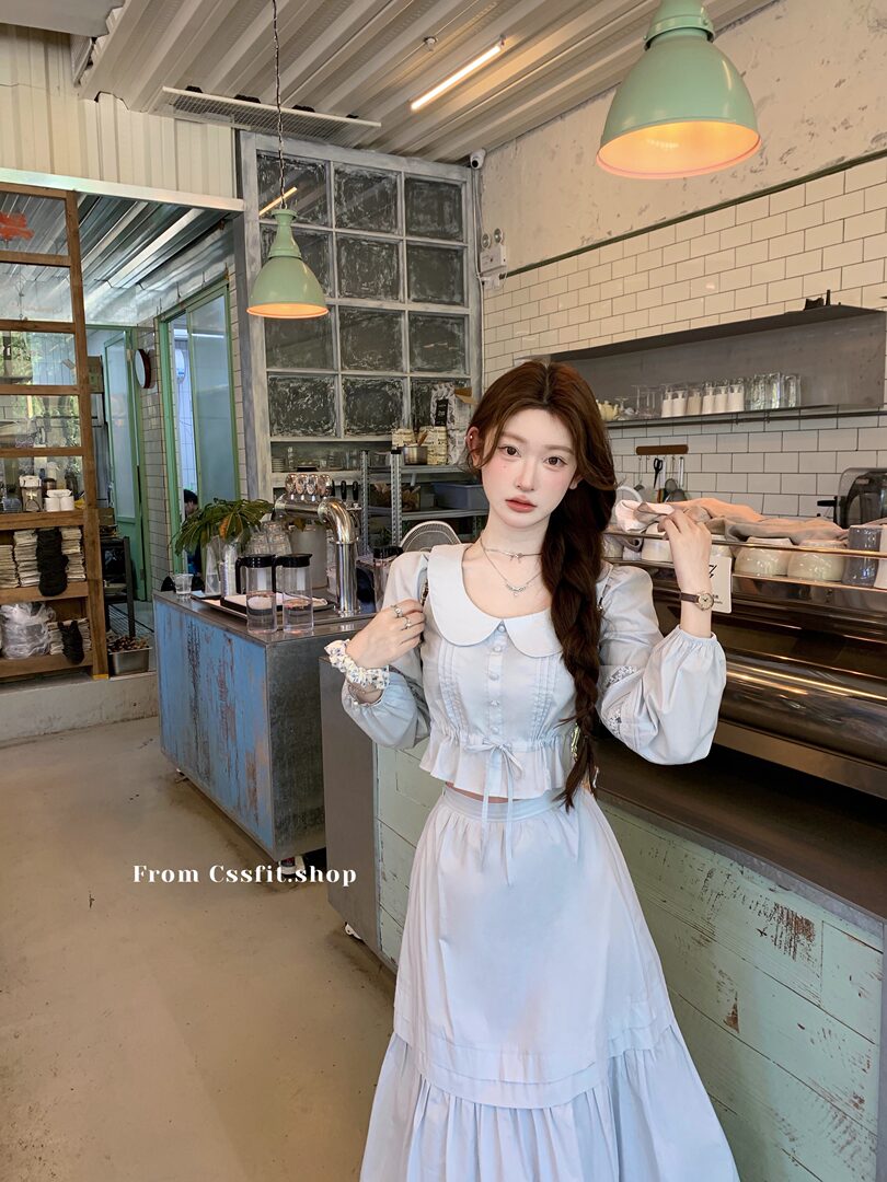 Woman wearing a light blue and white feminine long-sleeve dress set in a cafe