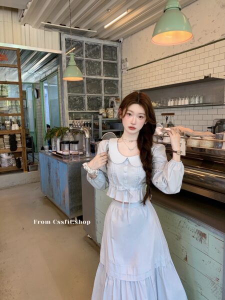Woman wearing a light blue and white feminine long-sleeve dress set in a cafe