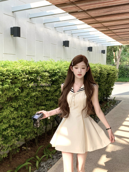 Young woman wearing a cream sleeveless sailor-style dress outdoors
