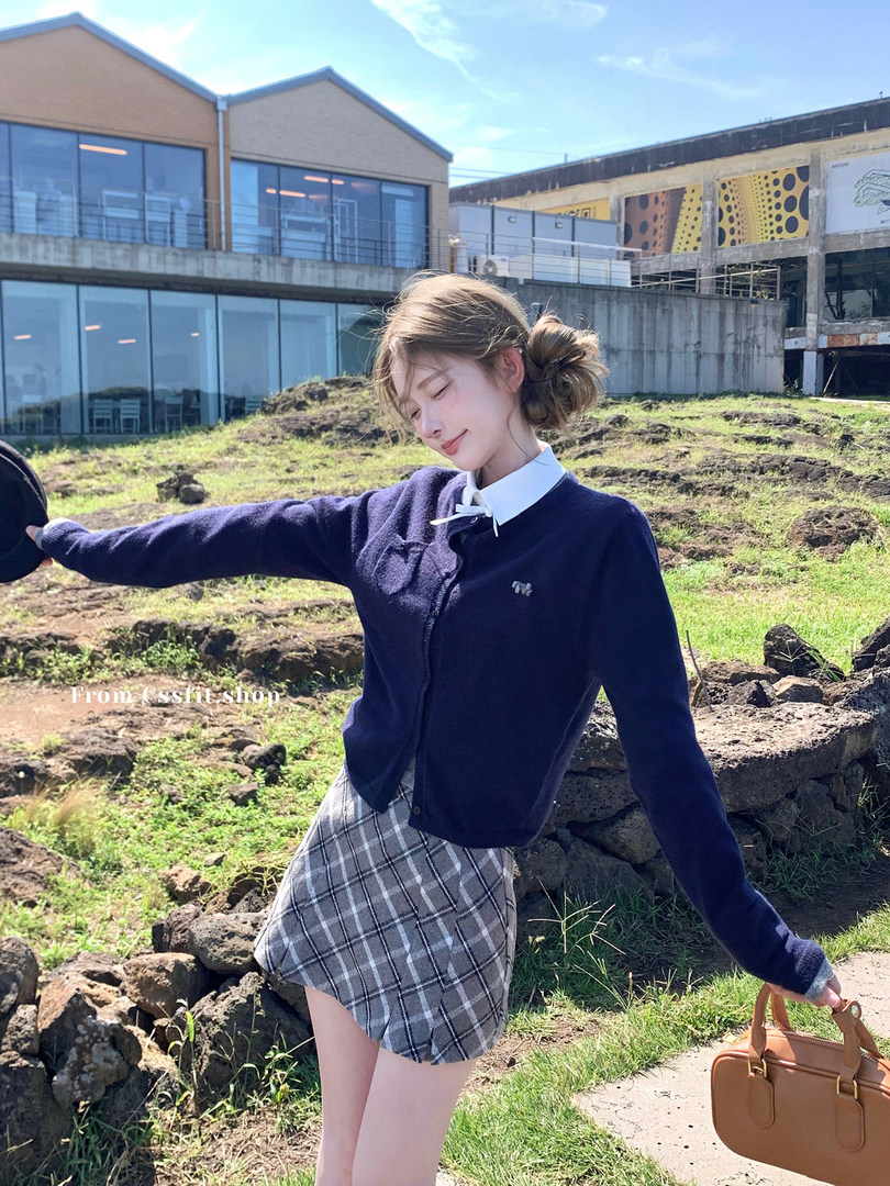 Woman wearing a navy cardigan and plaid mini skirt outdoors