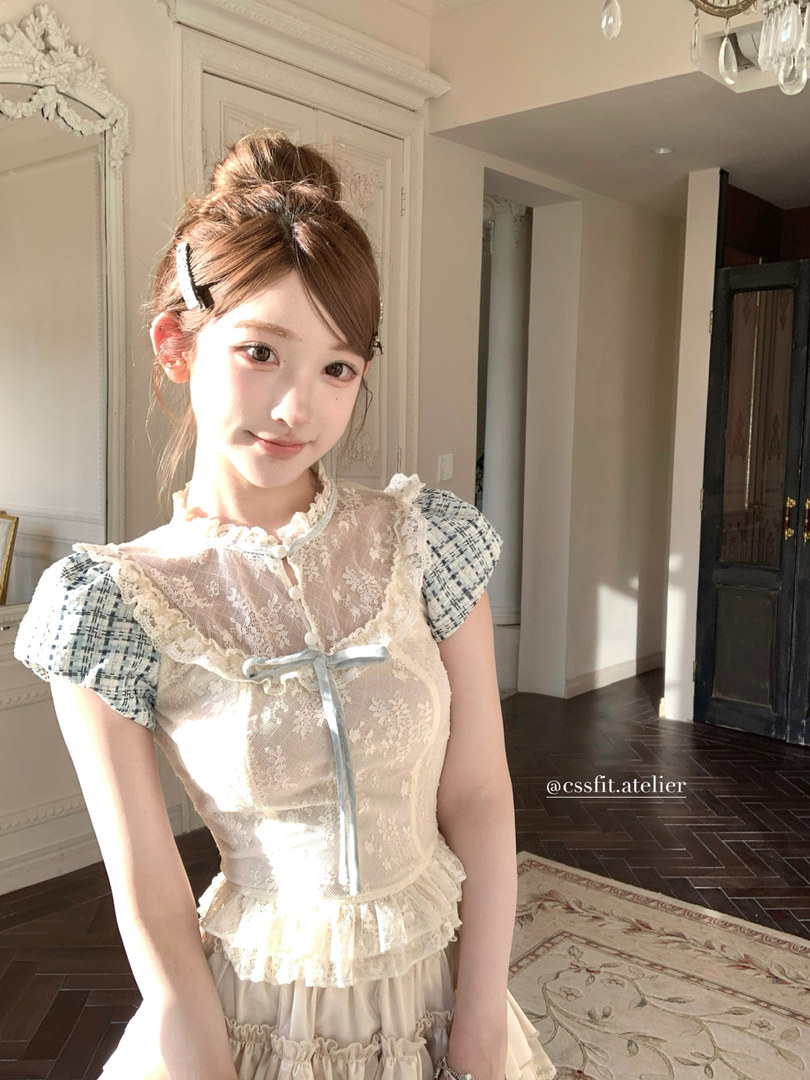 A young woman wearing a cream lace dress with puff sleeves and a bow detail