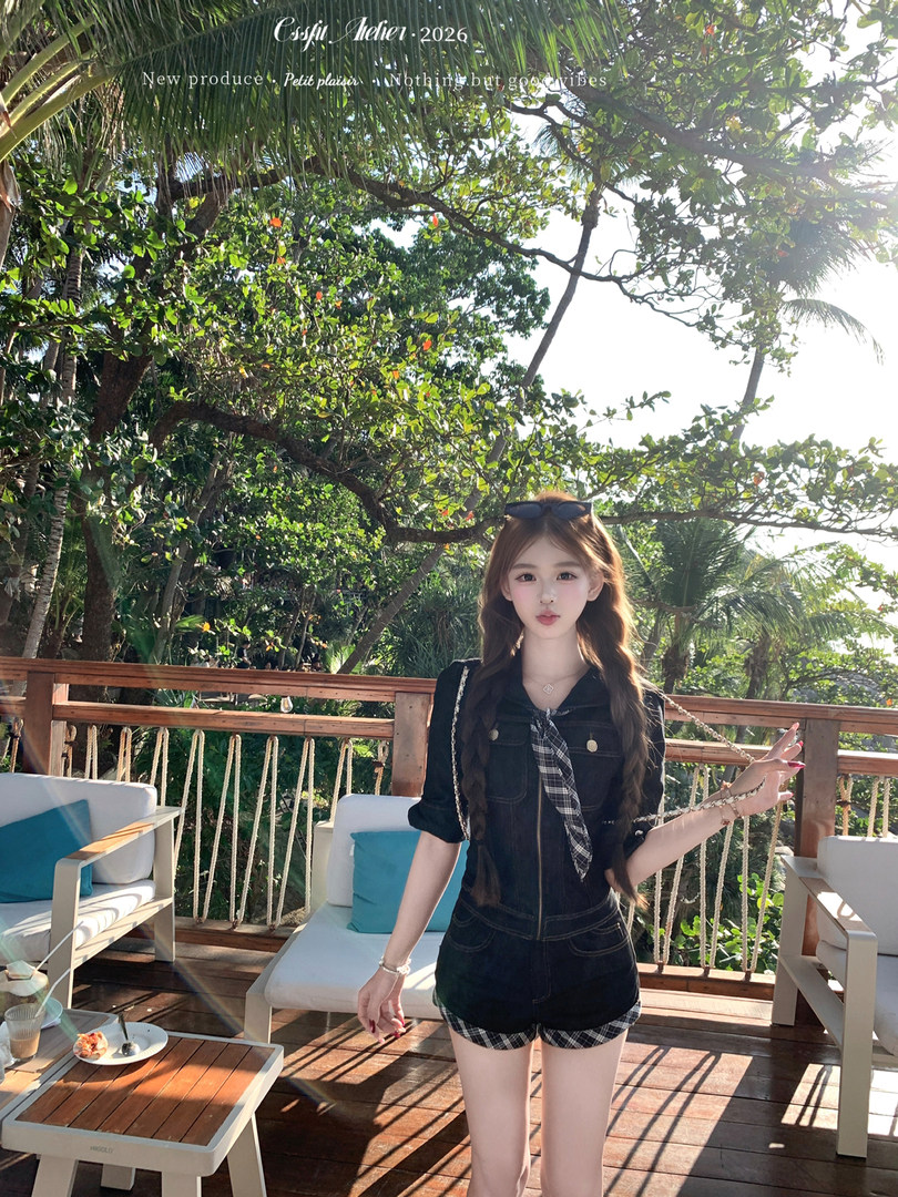 Woman wearing a black romper with plaid tie detail outdoors