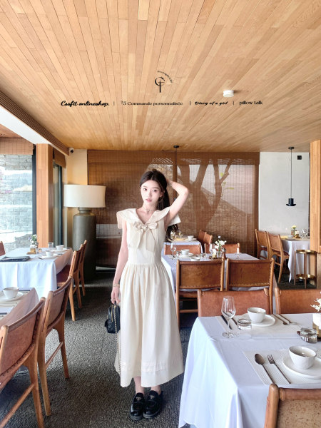 Woman wearing a cream sleeveless midi dress in a restaurant setting