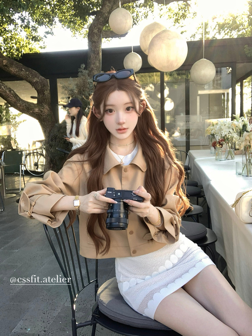 Woman wearing a beige cropped jacket and white textured shorts outdoors