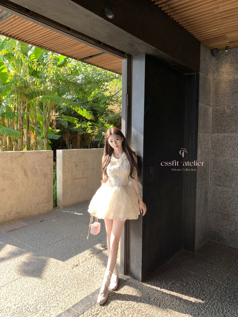 Model wearing a light cream sleeveless mini dress outdoors.
