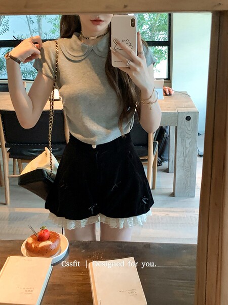 Woman wearing a gray sleeveless top with a black skirt in a mirror selfie